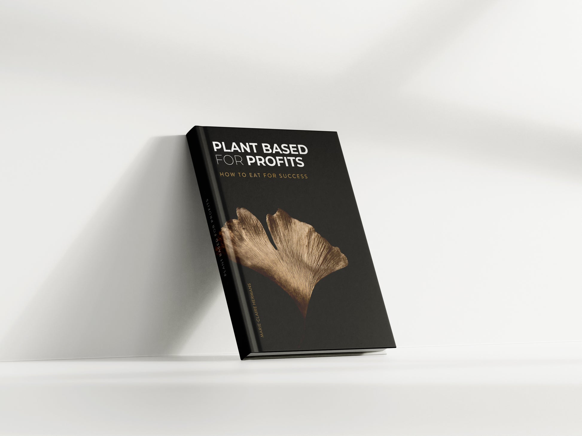 Plant Based for Profits Hardcover Book standing agains clean, white wall in sunlight- How to Eat for Success by Marie-Claire Hermans